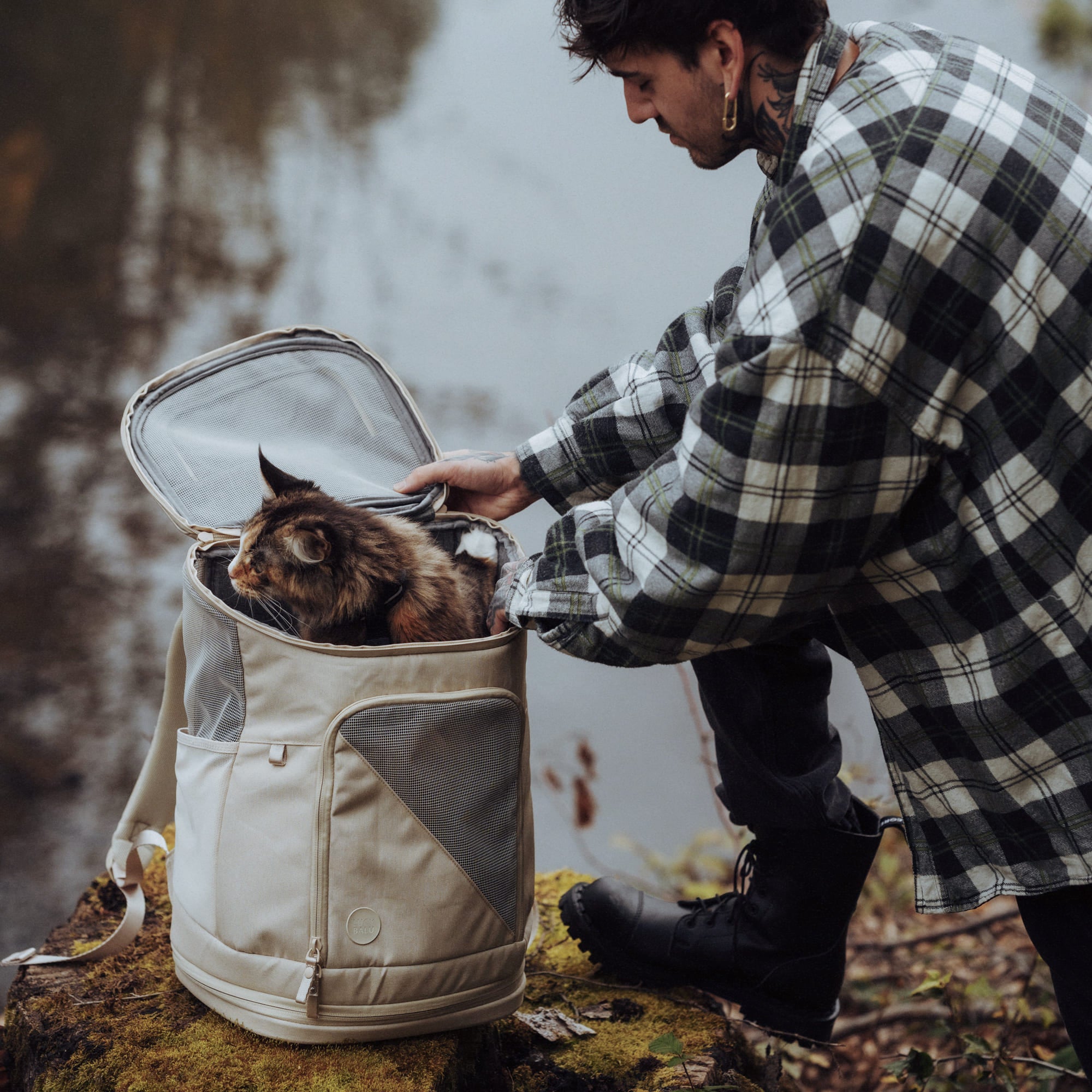 HOP-ON Katzenrucksack in Sand, Mann öffnet die Tasche bei einem Ausflug in der Natur, getigerte Katze schaut heraus