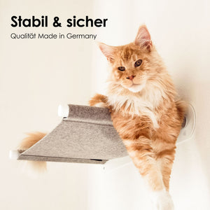 Große orangefarbene Katze liegt seitlich auf einer hellgrauen Wandhängematte mit weißen Wandhaltern – stabil & sicher.