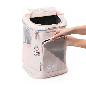 Hände öffnen die Vorderseite des rosa HOP-ON Katzenrucksacks Hello Kitty Edition mit Hello Kitty Anhänger